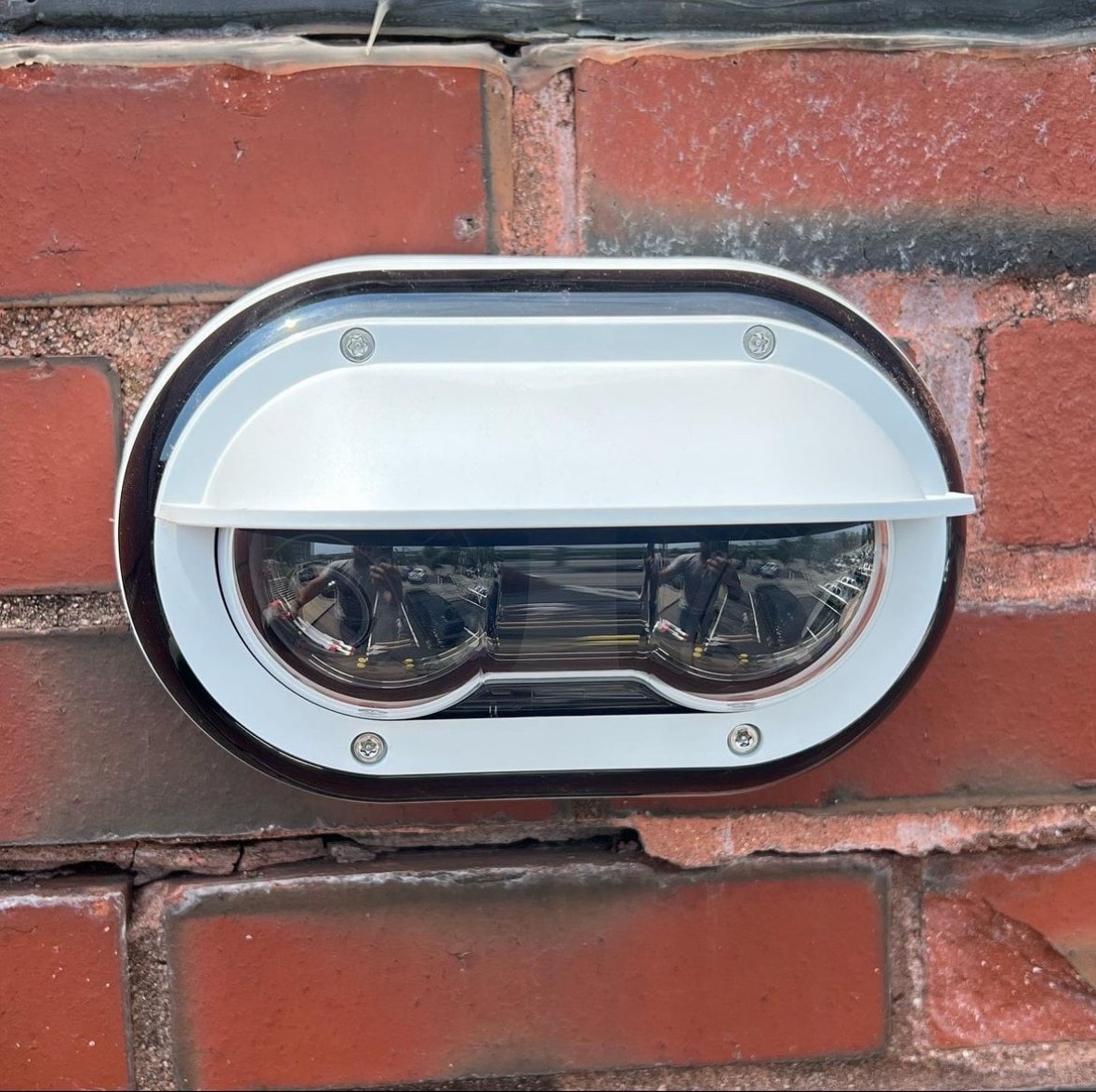 Dual-lens Axis outdoor security camera flush-mounted to brick exterior