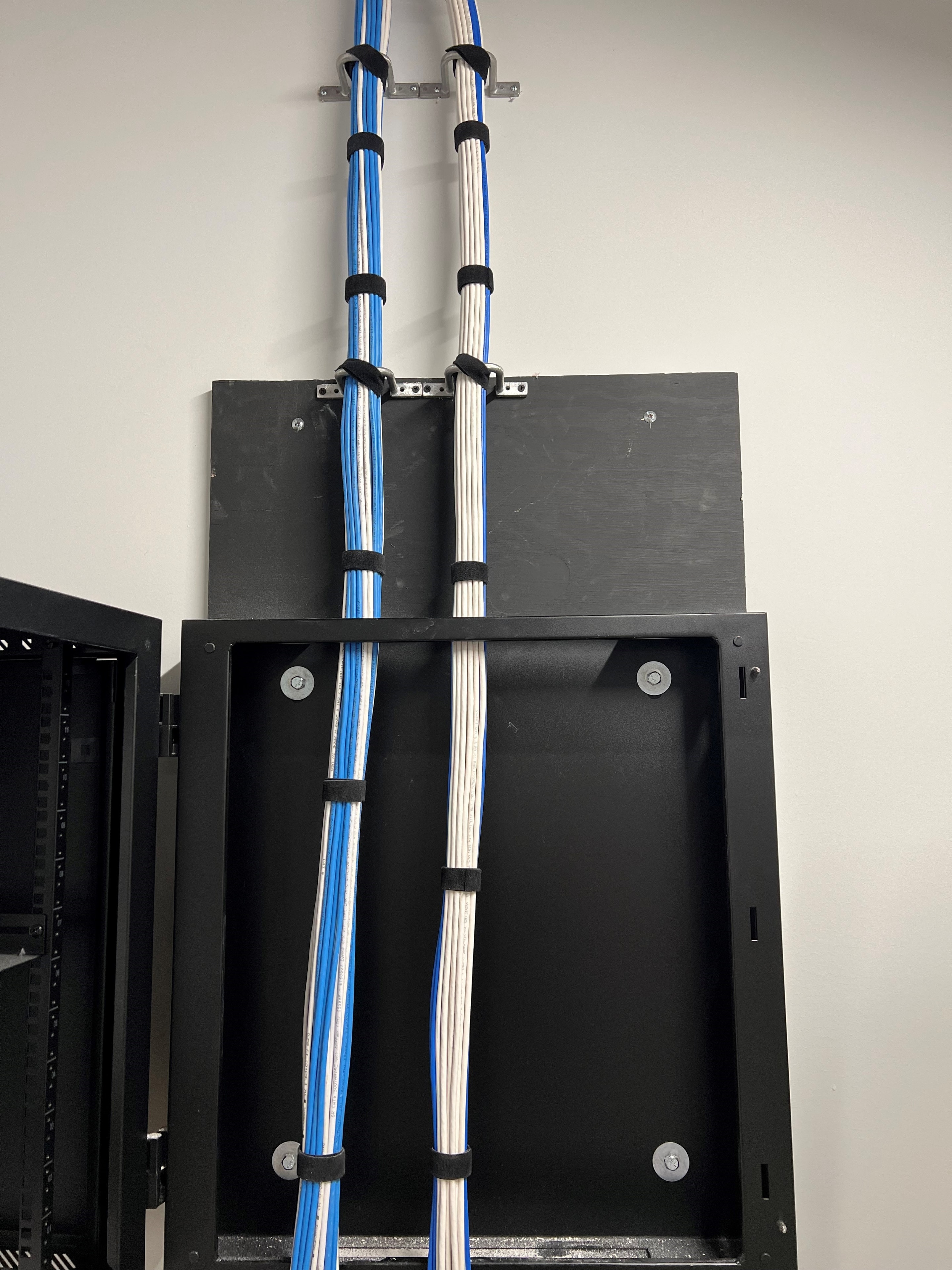 Dual-bundle structured cabling run between wall-mounted network enclosures