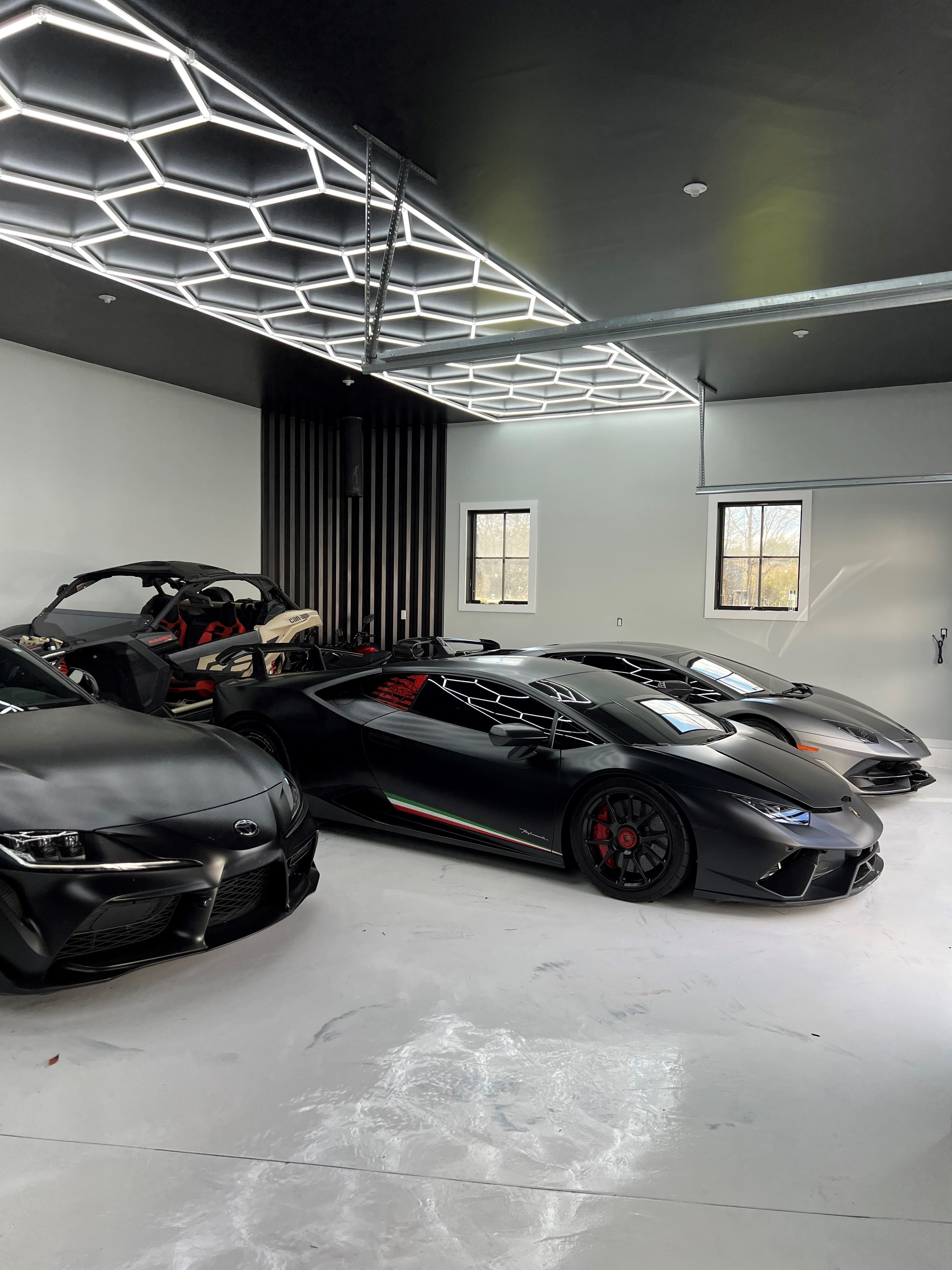 Hexagonal LED ceiling lighting over a luxury supercar collection
