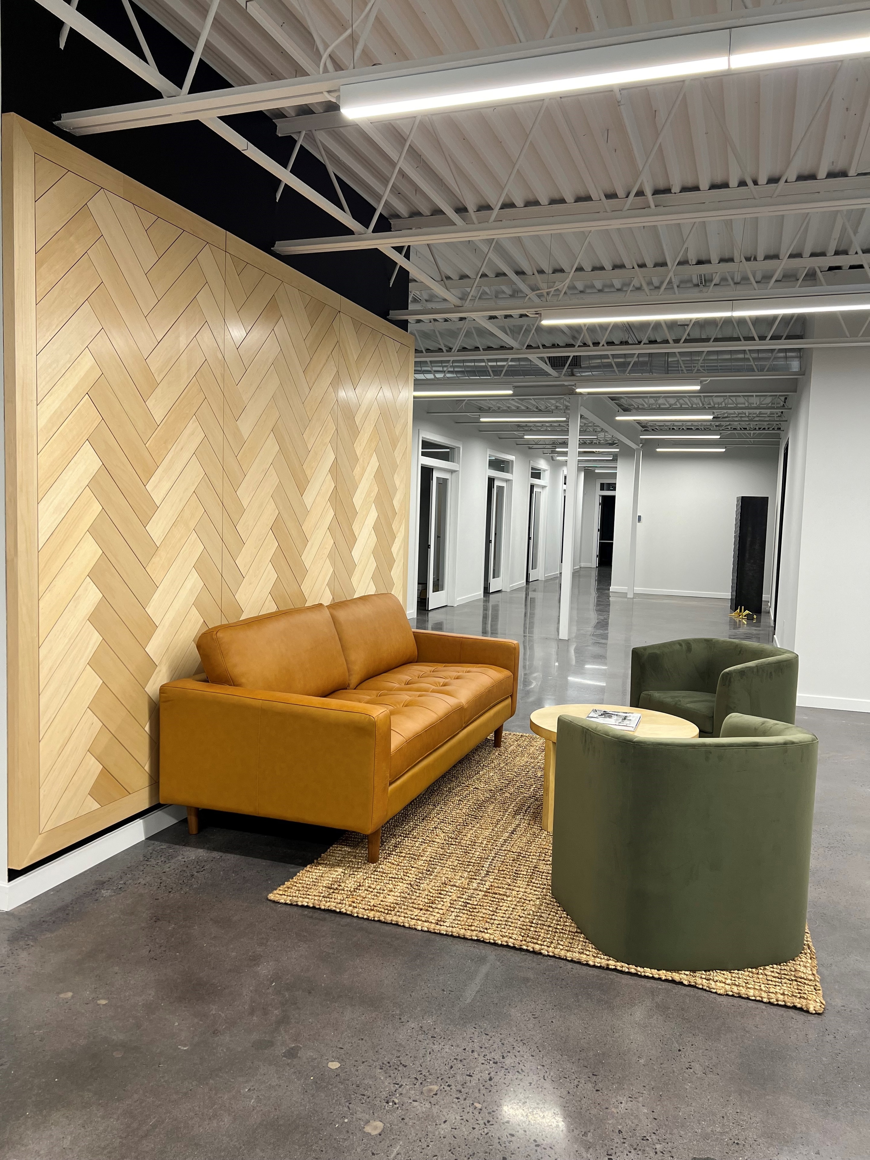 Herringbone wood accent wall with linear LED lighting in a commercial office lobby