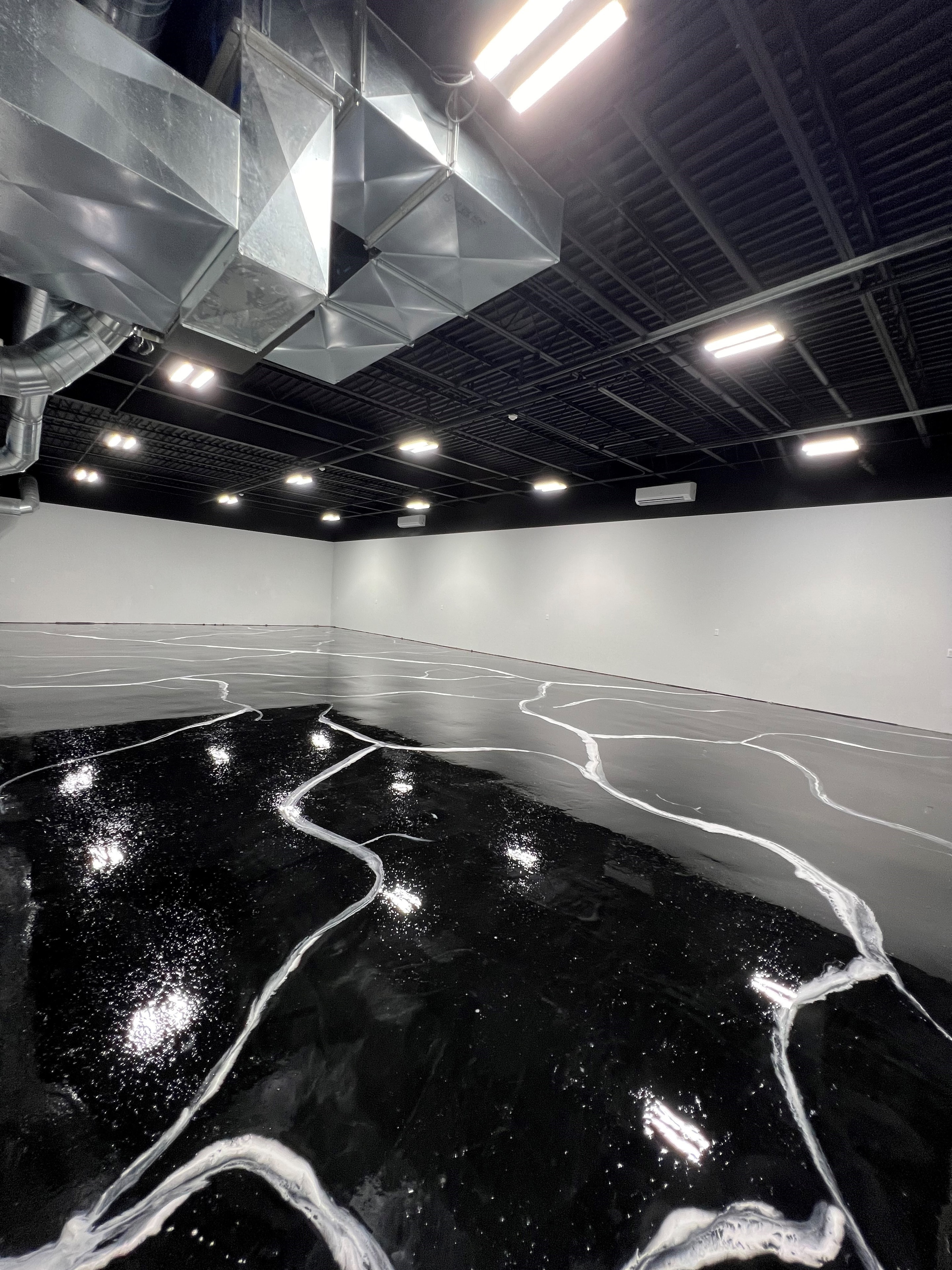 Black marble epoxy floor installation with high bay ceiling lighting
