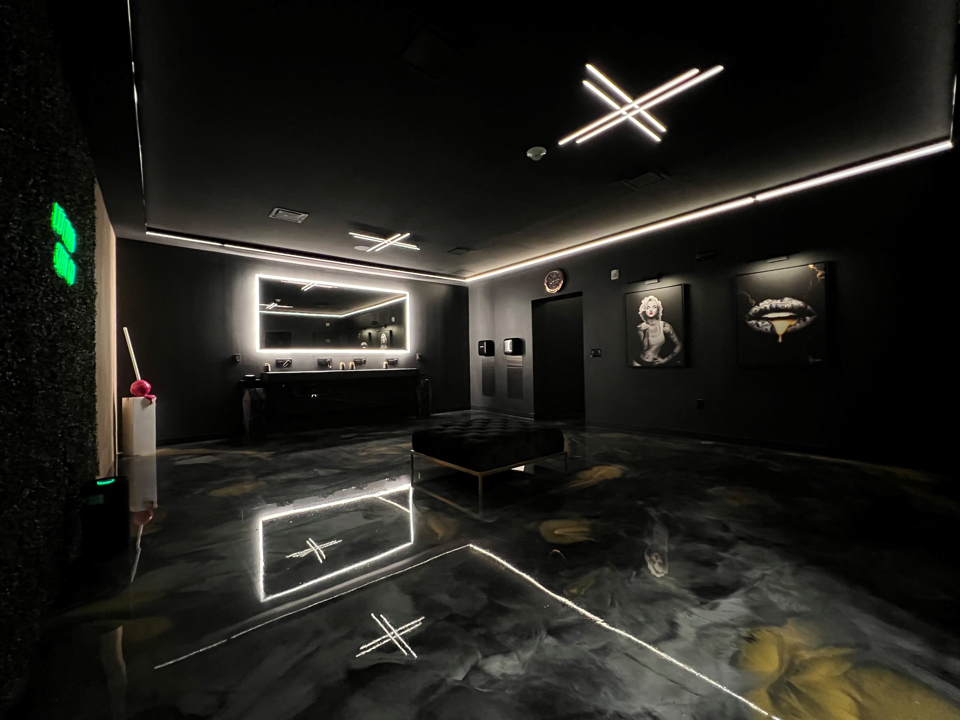 High-end bathroom with linear LED ceiling fixtures, backlit mirror, and epoxy floors
