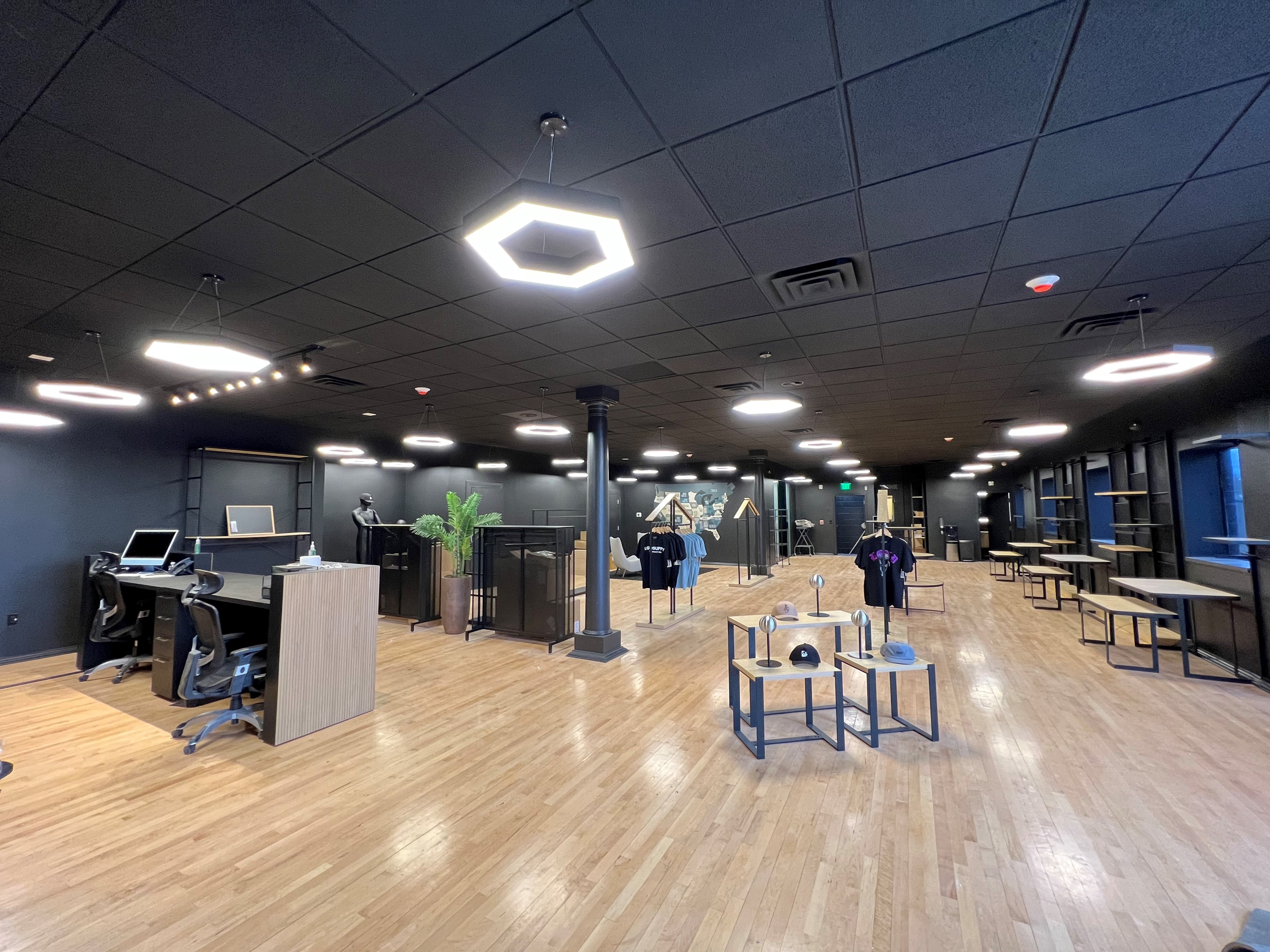 Hexagonal pendant lighting throughout a modern retail showroom with hardwood floors